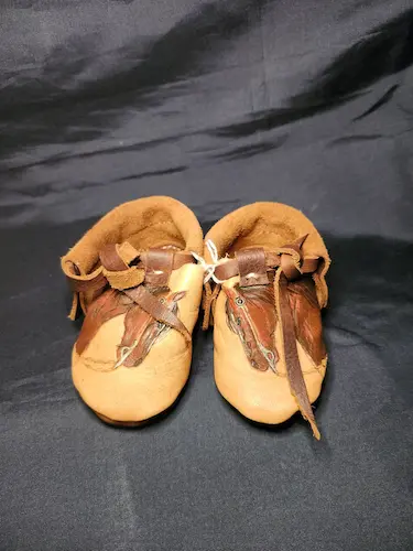 Handcrafted baby moccasins with a tooled horse on them